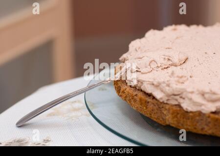 Processo di lavorazione della torta a casa. Primo piano di biscotto al cioccolato affettato con crema. Concetto di dessert delizioso e culinario. Foto Stock