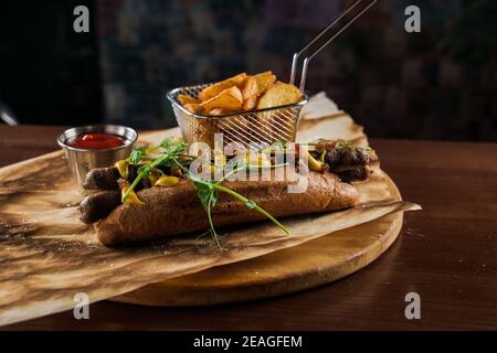 Barbecue hot dog alla griglia e birra con senape gialla e ketchup su sfondo di legno. Sandwich hot dog con patatine fritte e salse. Foto Stock