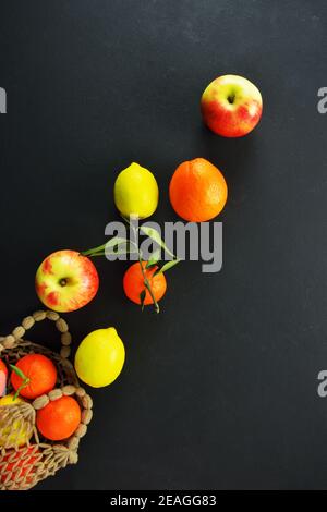 Sacchetto riutilizzabile con agrumi e mele su sfondo nero Foto Stock