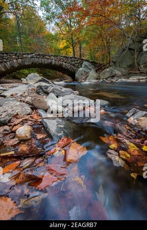 Il fogliame autunnale incornicia il Boulder Bridge nel Rock Creek Park, Washington, DC in autunno. Foto Stock