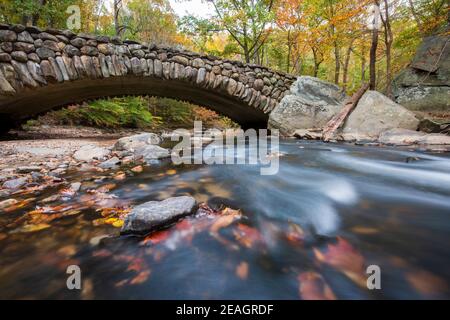 Il fogliame autunnale incornicia il Boulder Bridge nel Rock Creek Park, Washington, DC in autunno. Foto Stock