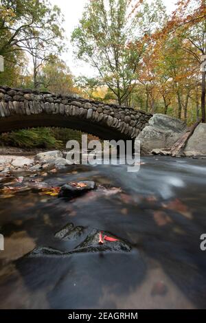 Il fogliame autunnale incornicia il Boulder Bridge nel Rock Creek Park, Washington, DC in autunno. Foto Stock