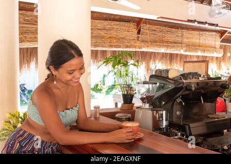 Giovane ragazza asiatica di Pretty che ha un caffè che beve un caffè Latte Cappuccino in una caffetteria Barista macchina da caffè Bright Mor Foto Stock