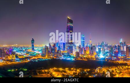 Vista aerea notturna del centro di Kuwait dominato dalla torre di liberazione. Foto Stock