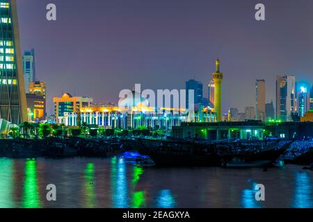 La Grande moschea del Kuwait dietro un porto dhow vicino al souq Sharq in Kuwait druing notte. Foto Stock