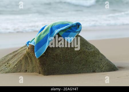 Vacanza in spiaggia, natura morta, oggetto, concetto di vacanza, asciugamano sdraiato su roccia, asciugandosi dopo il nuoto in mare, illustrazione di vacanza, cose Foto Stock