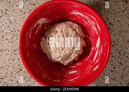 Una palla di impasto in un recipiente rosso. Serie step-by-step per la preparazione di pane fatto in casa. Quadro 4 di 13 Foto Stock