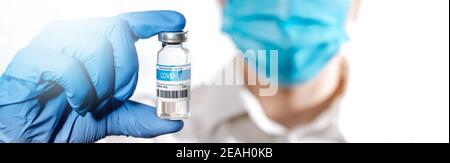 Foto panoramica ravvicinata della mano del medico contiene la fiala con il vaccino COVID-19 del coronavirus. Vaccino Corona virus per COVID. Concetto di medicina, sperimentazione e trattamento dovuto al coronavirus SARS-COV-2 Foto Stock