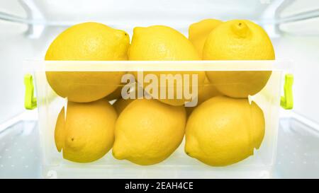 Frigorifero fresco limone limonata detox succo frutta matura in cassetta di plastica frigorifero. Contenitori di conservazione di cibo Limoni frigorifero sano mangiare frutta fresca Foto Stock