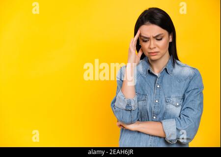 Turbata giovane donna caucasica, è triste a causa di mal di testa, depressione, stress o problemi personali, si trova su sfondo arancione isolato, toccare la testa con la mano Foto Stock
