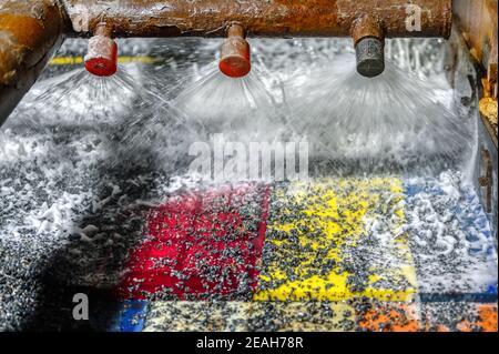 Schermo vibrante, lavaggio con liquido. Il liquido viene versato in un flusso simile a un ventilatore da appositi ugelli Foto Stock