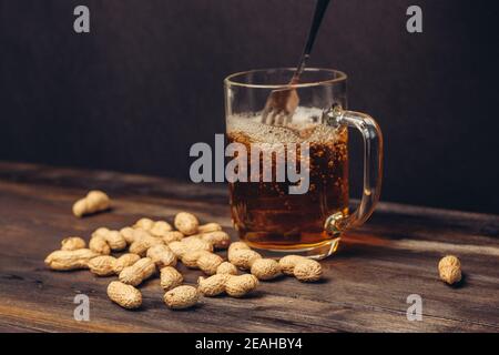 tazza di birra su un tavolo di legno arachidi in conchiglie primo piano su bevande alcoliche Foto Stock