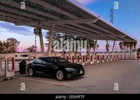 Firebaugh, USA - 21 gennaio 2021: Auto elettrica nera di lusso Tesla Model S 75D ad un Supercharger da 250 kW sulla California Highway 5 al tramonto Foto Stock