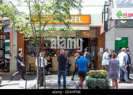 Lavoratori dell'ufficio di Sydney in attesa del pranzo da asporto ordine da falafel ristorante cafe su george Street in citta', Sydney, Australia Foto Stock