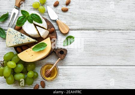 Diversi tipi di formaggio con spuntini su un vecchio bianco tavolo di legno Foto Stock