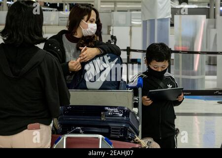 Tokyo, Giappone. 07 febbraio 2021. Madre e figlio indossano maschere come misura preventiva contro la diffusione della linea Covid-19 presso un punto di check-in all'aeroporto di Narita. Poiché l'aumento delle infezioni da coronavirus di Covid-19, le autorità giapponesi hanno chiuso i confini per la maggior parte dei viaggiatori. Credit: SOPA Images Limited/Alamy Live News Foto Stock