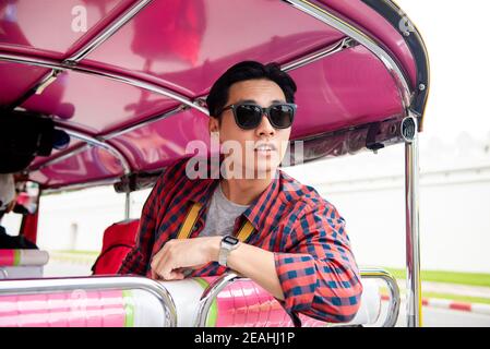 Giovane turista asiatico che cavalcava un taxi locale Tuk Tuk A Bangkok Thailandia Foto Stock