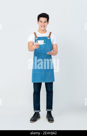 Tutta la lunghezza di un bel barista asiatico che sorrideva il servizio servire una tazza di caffè isolato su sfondo bianco Foto Stock