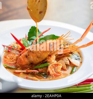 Tradizionale famoso cibo tailandese Tom Yum Kung o caldo e. zuppa piccante di gamberi con ingredienti misti di erbe in un recipiente Foto Stock