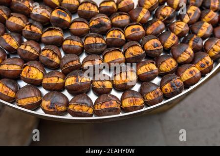 Castagne arrostite ben disposte su un vassoio di ferro Foto Stock