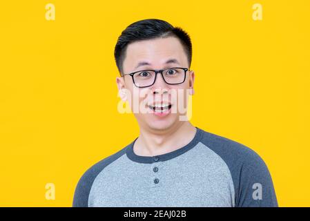 Primo piano ritratto di un sorprendente giovane asiatico isolato su sfondo giallo Foto Stock