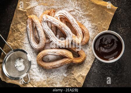 Gustosi churros fritti con zucchero in polvere e salsa al cioccolato. Foto Stock