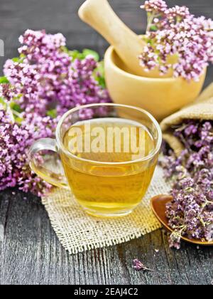 Tè di origano in tazza con mortaio su legno scuro scheda Foto Stock