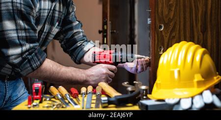 Falegname al lavoro ripara e installa la serratura della porta. Carpenteria. Foto Stock