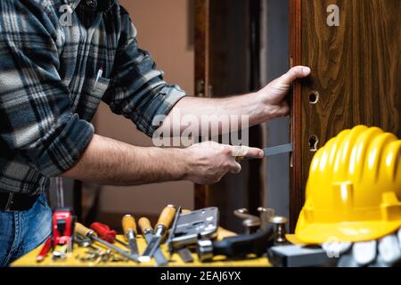 Falegname al lavoro ripara e installa la serratura della porta. Carpenteria. Foto Stock