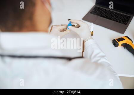 Immagine messa a fuoco delle braccia del medico con il farmaco medico in esso di fronte al dispositivo moderno Foto Stock