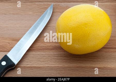 primo piano su un coltello da taglio in legno e limone fresco giallo. Foto Stock