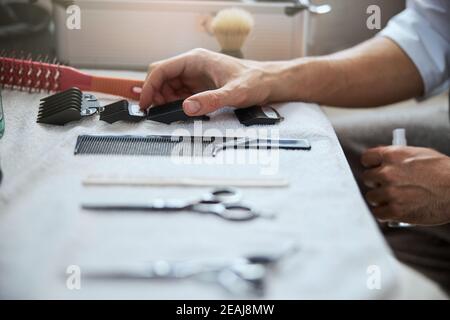 Hairstylist maschio che pulisce il suo posto di lavoro prima del cliente dentro salone di bellezza Foto Stock