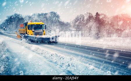 Spazzaneve autocarro pulendo strada nevosa in tempesta di neve Foto Stock