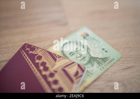 Twenty Thai Baht Bill in parte all'interno di un passaporto svedese Foto Stock