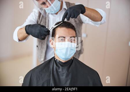 Bel maschio indiano con capelli scuri che ottiene nuovo styling dentro barbiere Foto Stock