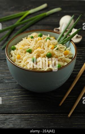 Piatto con tagliatelle, ingredienti e bastoncini su fondo di legno Foto Stock