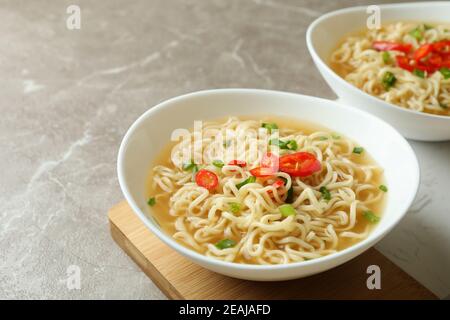 Concetto di mangiare gustoso con ciotole di tagliatelle in grigio sfondo Foto Stock