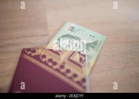 Twenty Thai Baht Bill in parte all'interno di un passaporto svedese Foto Stock