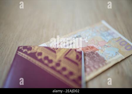 100 Dirhams Bill marocchino parzialmente all'interno di un passaporto svedese Foto Stock