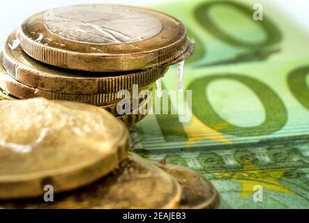 100 euro di banconote e monete in euro congelate in ghiaccio. Soldi congelati, euro in ghiaccio con le ciclicelle appesi giù Foto Stock