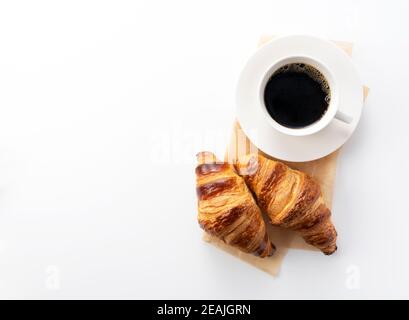 Croissant e caffè caldo su sfondo bianco Foto Stock