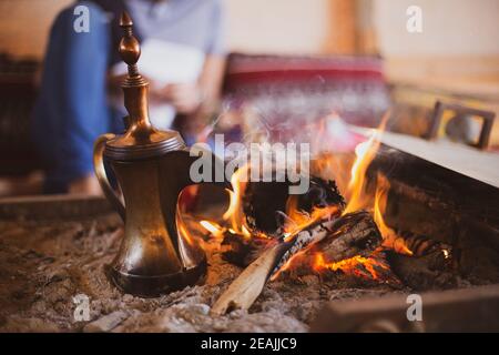 Tradizionale caffettiera arabica chiamata dallah nel camino all'interno del tenda Foto Stock