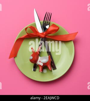 piastra rotonda, forcella e coltello in metallo legati con un nastro di seta rosso Foto Stock