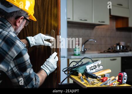 Falegname al lavoro ripara e installa la serratura della porta. Carpenteria. Foto Stock