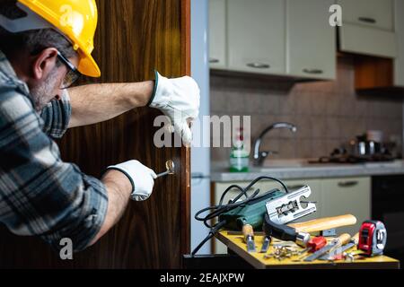 Falegname al lavoro ripara e installa la serratura della porta. Carpenteria. Foto Stock