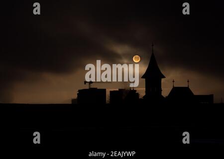 Svetta l'alba con nebbia e cielo scuro con la silhouette della chiesa e costruzione di edifici Foto Stock
