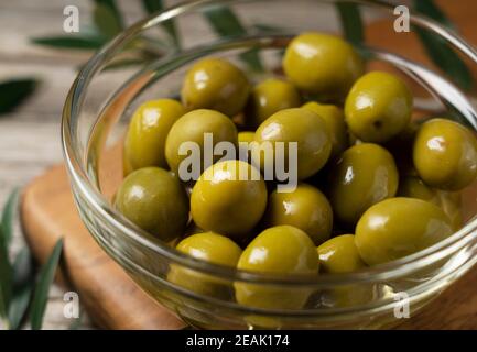 Rami di olive con olive salate poste su uno sfondo di vecchie tavole di legno Foto Stock