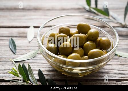 Rami di olive con olive salate poste su uno sfondo di vecchie tavole di legno Foto Stock