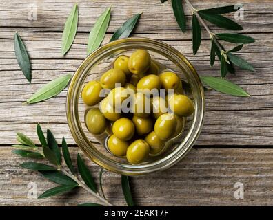 Rami di olive con olive salate poste su uno sfondo di vecchie tavole di legno Foto Stock