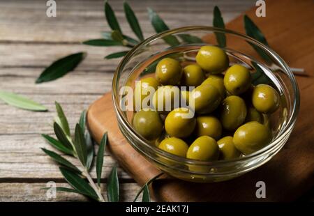 Rami di olive con olive salate poste su uno sfondo di vecchie tavole di legno Foto Stock